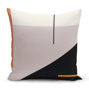 May include: Square decorative pillow with a geometric design. The pillow features a color block pattern with sections of cream, gray, and black. A vertical black line and a horizontal gold line accent the design. The pillow has a rust-colored border.