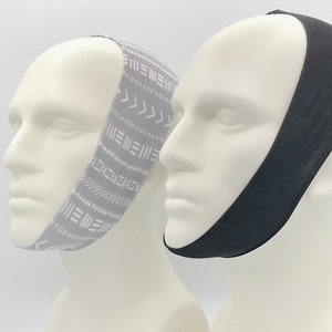 May include: Two mannequins wearing chin straps. One strap is black and the other is gray with a white geometric pattern.