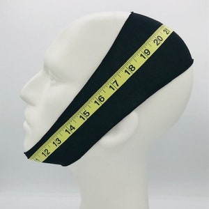 This is an image of a mannequin wearing the CPAP chin strap as well as a soft measuring tape wrapped around the outside of the chin strap as a guide to finding your measurement.