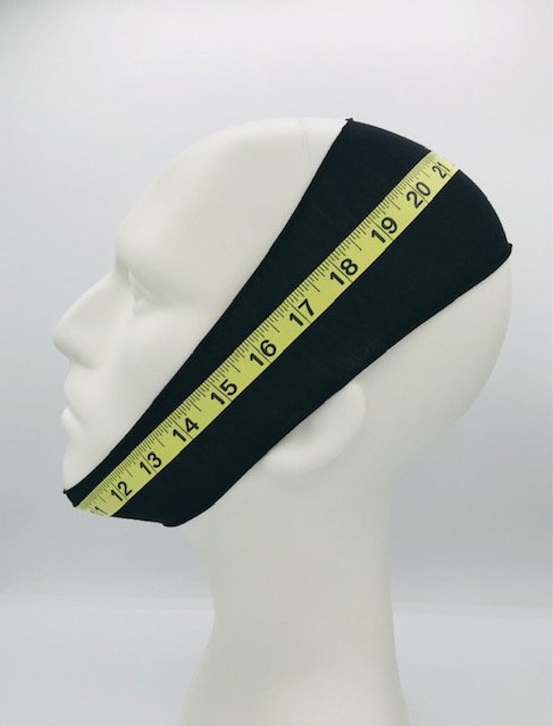 This is an image of a mannequin wearing the CPAP chin strap as well as a soft measuring tape wrapped around the outside of the chin strap as a guide to finding your measurement.
