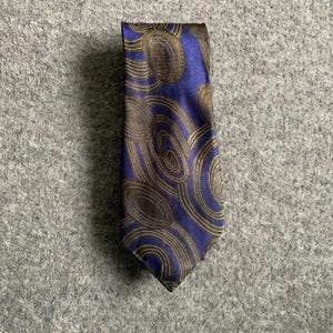 May include: A blue silk tie with a brown and gold abstract pattern.