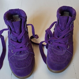 May include: A pair of purple suede high-top sneakers with purple laces.