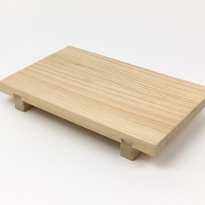 May include: A natural wood serving tray with four small legs. The tray is rectangular and has a light wood grain.