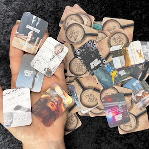 May include: A selection of small, rectangular cards with diverse images and text. Some cards display images of individuals, while others have text such as "Obstruction" and "Framed." The cards are themed around solving mysteries, with a magnifying glass logo.