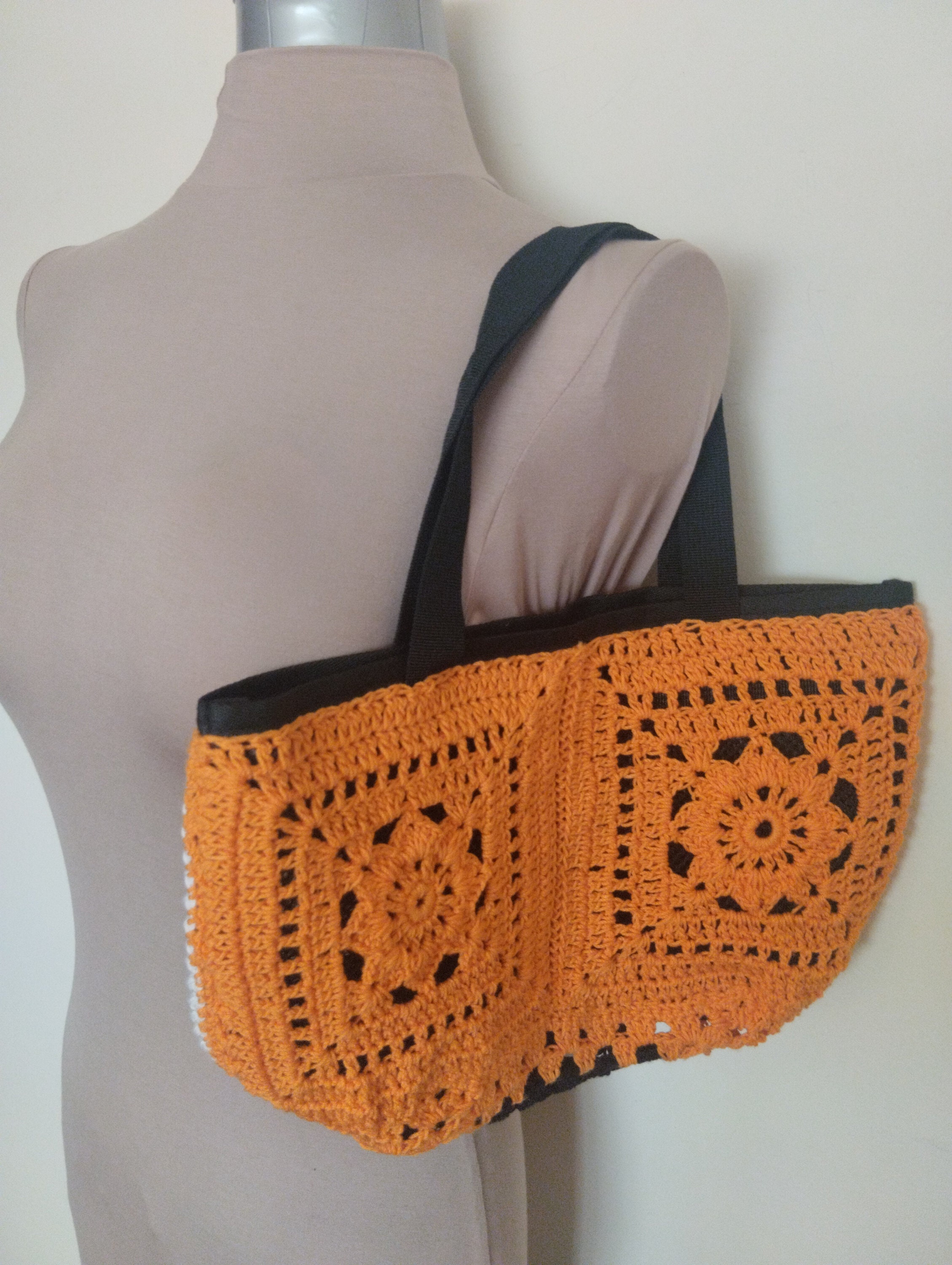 Handgefertigte Häkelhandtasche in Orange, Weiß und Schwarz.