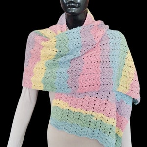 Könnte beinhalten: Ein regenbogenfarbener gestrickter Schal mit einem Farbmuster in Hellblau, Grün, Gelb, Rosa und Lila.