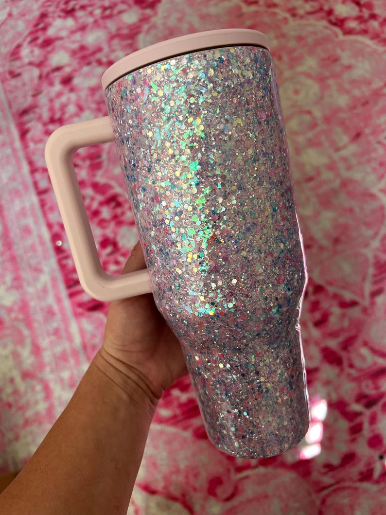 Puede incluir: Vaso cubierto de purpurina con asa y tapa. El vaso est&aacute; cubierto de purpurina iridiscente, con un asa y tapa de color rosa claro. Dise&ntilde;ado para contener bebidas.