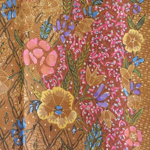 May include: Brown fabric with a floral pattern. The pattern features pink, yellow, blue, and purple flowers on a brown background. The fabric has a diamond-shaped pattern.