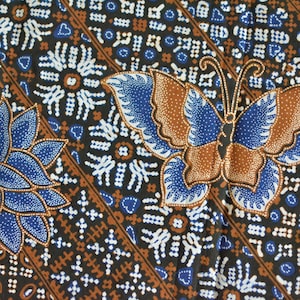May include: A black fabric with a blue and brown butterfly pattern. The butterfly has white accents and is surrounded by a repeating pattern of small white dots and brown lines.