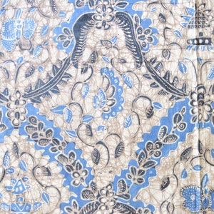 May include: Close-up of a fabric with a repeating floral pattern in blue, grey, and off-white. The design features stylized flowers, leaves, and geometric shapes, creating a symmetrical and ornate appearance. The fabric has a textured look.