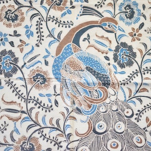 Peut inclure: Textile crème avec un motif de paon et des motifs floraux et de feuilles. Le paon est représenté dans des tons de marron et de bleu, avec une queue détaillée. Les éléments floraux sont bleus et marron, créant un textile décoratif.