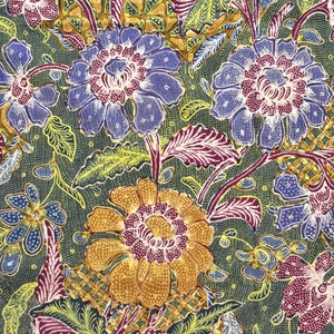 Könnte beinhalten: Nahaufnahme eines Stoffes mit floralem Muster. Das Design zeigt große, stilisierte Blumen in Blau-, Gold- und Burgundertönen vor einem dunkelgrünen Hintergrund. Der Stoff hat ein strukturiertes Aussehen.