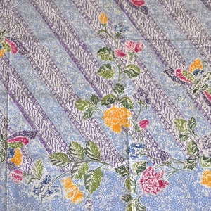 Puede incluir: Una tela azul con un diseño estampado blanco y morado. El patrón presenta mariposas, flores y hojas.