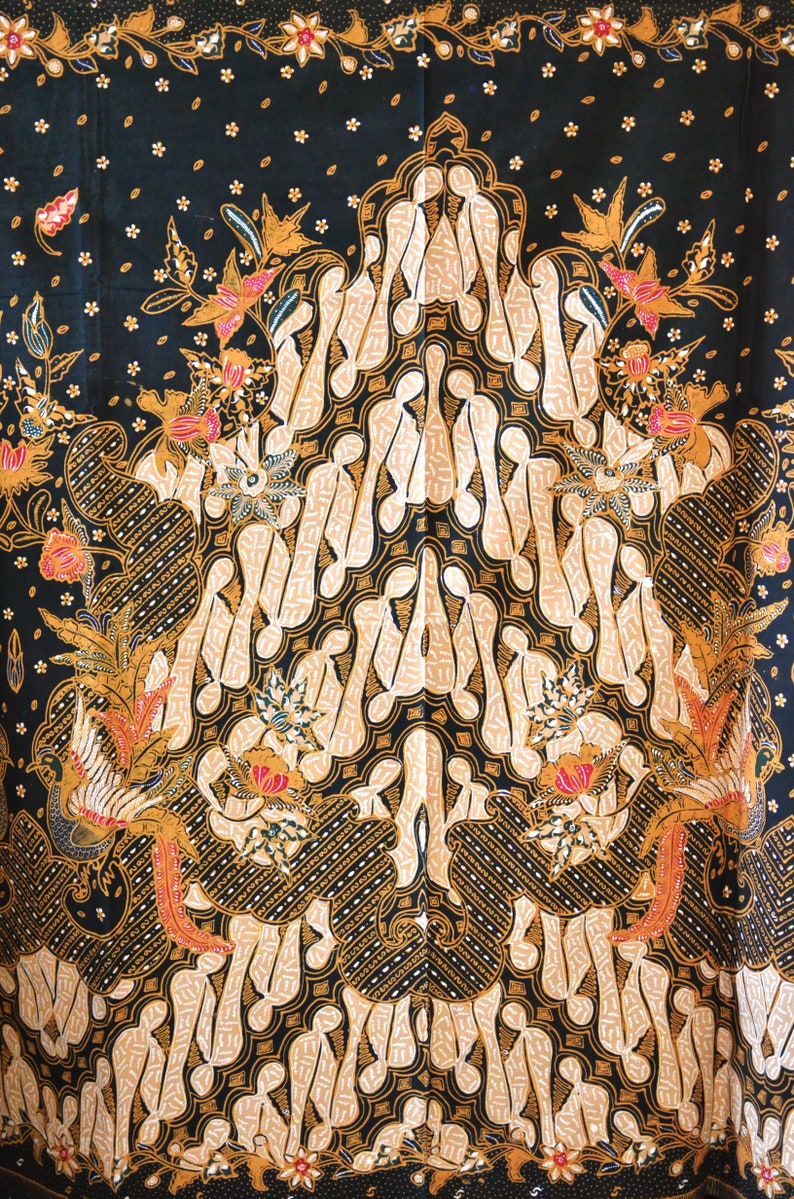 May include: A black fabric with a traditional Indonesian batik pattern. The pattern features a large central motif of stylized figures in beige and gold, surrounded by smaller floral and bird motifs. The background is a dark black with small white dots.