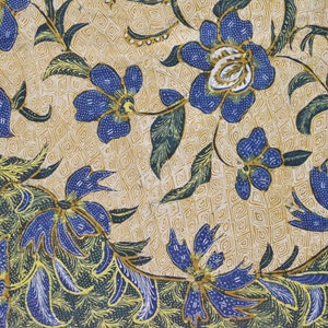 May include: A close-up of a fabric with a blue and gold floral pattern. The fabric has a repeating pattern of flowers and leaves. The background is a light beige color.