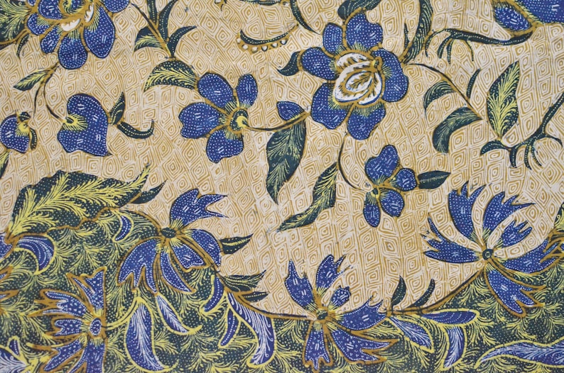 May include: A close-up of a fabric with a blue and gold floral pattern. The fabric has a repeating pattern of flowers and leaves. The background is a light beige color.