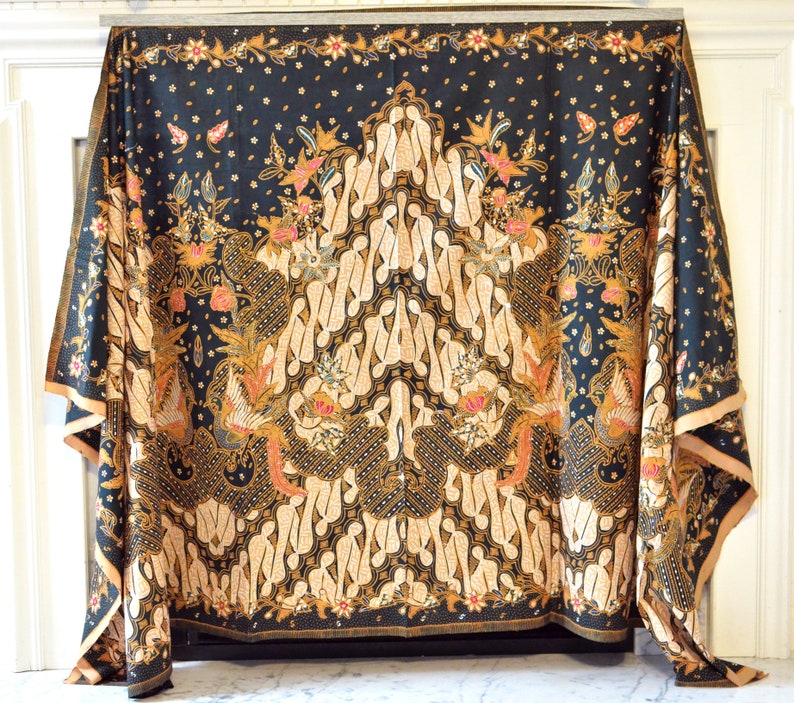 May include: A black and gold patterned fabric with a traditional Indonesian batik design. The fabric features intricate floral and geometric motifs.