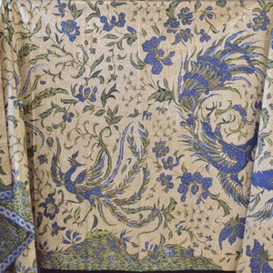 May include: A cream-colored fabric with a blue and green floral pattern. The pattern features peacocks with their tails spread out.