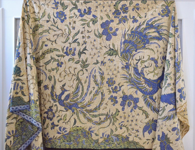 May include: A cream-colored fabric with a blue and green floral pattern. The pattern features peacocks with their tails spread out.