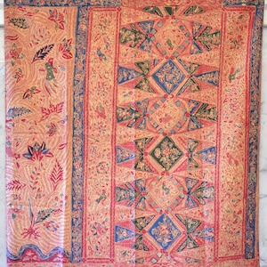 Könnte beinhalten: Ein roter, blauer und grüner Stoff mit geometrischem Muster. Der Stoff hat ein Blumenmuster und ein sich wiederholendes Muster aus Dreiecken und Rauten.