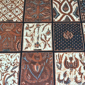 Könnte beinhalten: Eine Nahaufnahme eines braunen und weißen Stoffes mit einem sich wiederholenden Muster aus komplizierten Designs. Der Stoff ist in Quadrate unterteilt, jedes mit einem anderen Design. Die Designs bestehen aus kleinen, detaillierten Mustern, darunter Blumen, Blätter und geometrische Formen. Der Stoff hat ein traditionelles, handgefertigtes Aussehen.