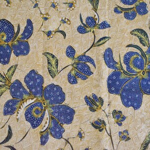 May include: A beige fabric with a repeating pattern of blue and yellow flowers. The flowers are stylized and have a geometric design.