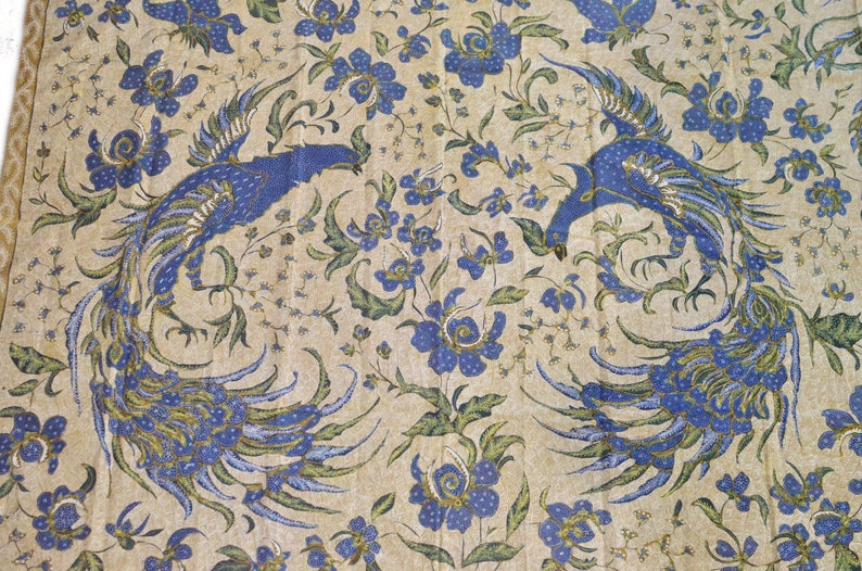 May include: A beige fabric with a blue and green floral pattern featuring two peacocks facing each other.