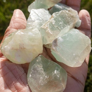 May include: A collection of green and white fluorite crystals in various shapes and sizes. The crystals are translucent and have a slight shimmer.
