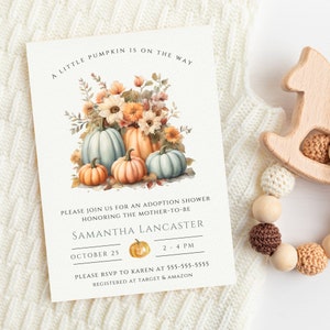 May include: A white card with a fall-themed adoption shower invitation. The card features a watercolor illustration of pumpkins and flowers. The text reads "A little pumpkin is on the way. Please join us for an adoption shower honoring the mother-to-be Samantha Lancaster. October 25, 2-4 PM. Please RSVP to Karen at 555-555-5555. Registered at Target & Amazon."