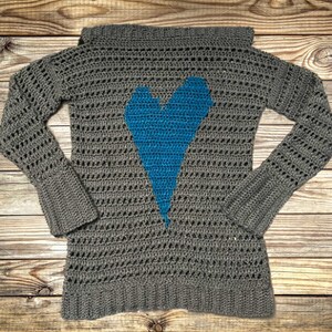 Pu&ograve; includere: Maglia a uncinetto grigia con un design a forma di cuore blu. La maglia ha una vestibilit&agrave; ampia e maniche lunghe.
