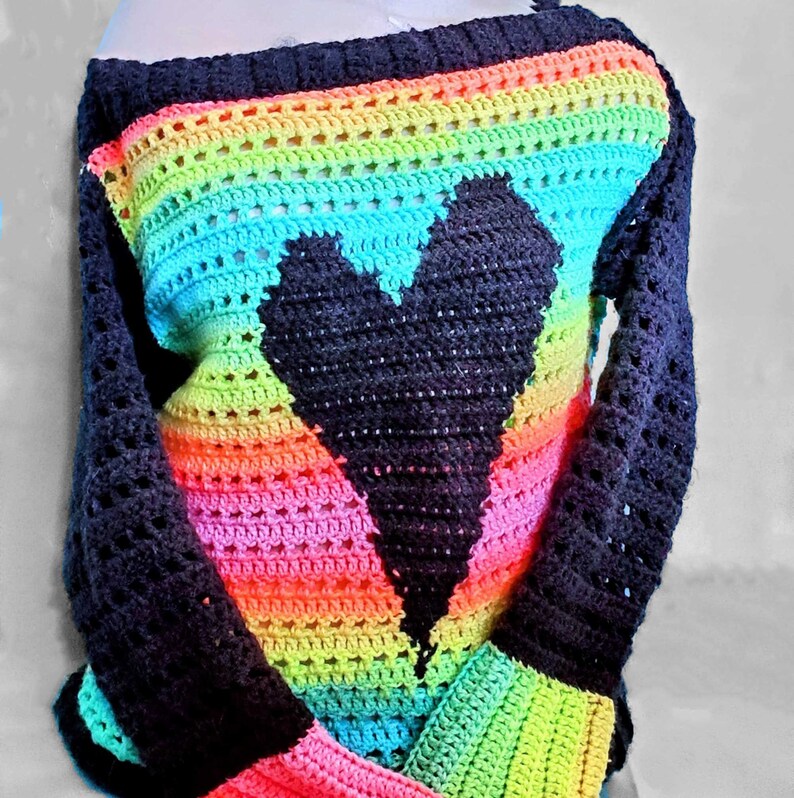 Pu&ograve; includere: Un top all'uncinetto arcobaleno con un design a forma di cuore nero. Il top ha una scollatura ampia e maniche lunghe.