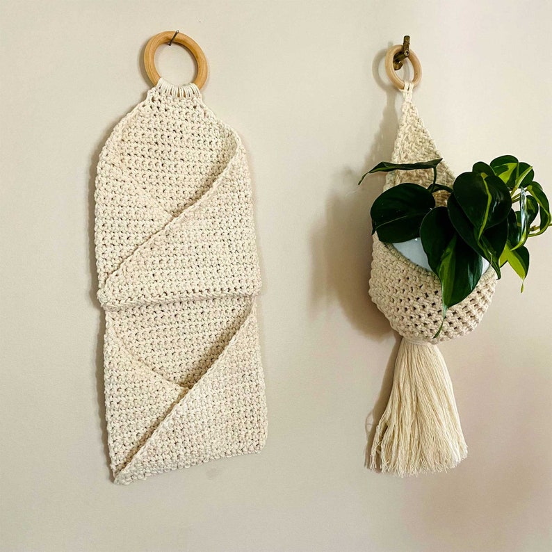 Pu&ograve; includere: Due portavasi in macram&egrave;, uno con un anello di legno in cima e l'altro con una pianta sospesa. Entrambi sono realizzati in corda di cotone beige naturale.