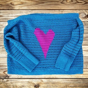 Pu&ograve; includere: Un maglione di lana blu con un design a forma di cuore rosa.