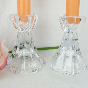 May include: Two clear glass candle holders with a faceted design. The holders are empty and have a round base.