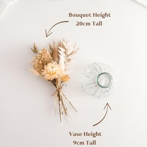 May include: A small dried flower bouquet with a light yellow and beige color palette, tied with twine. Next to it is a clear, ribbed glass vase. The bouquet is 20cm tall, and the vase is 9cm tall.