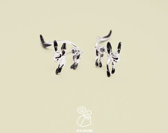May include: A pair of silver earrings with black accents shaped like a rabbit. The rabbit is standing on its hind legs with its tail curled up.