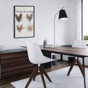 May include: A black framed poster with the title "Deep Breathing" and a diagram of four hearts with arrows showing the steps of deep breathing. The poster is hanging on a white wall in a modern office setting with a wooden desk, two white chairs, and a black floor lamp.