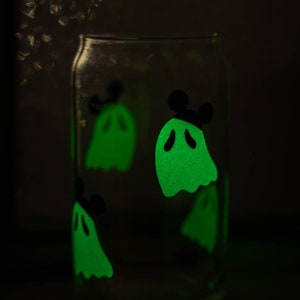 May include: A clear glass jar with glow-in-the-dark ghost stickers. The ghosts are green and have black eyes and mouths. One ghost has Mickey Mouse ears.