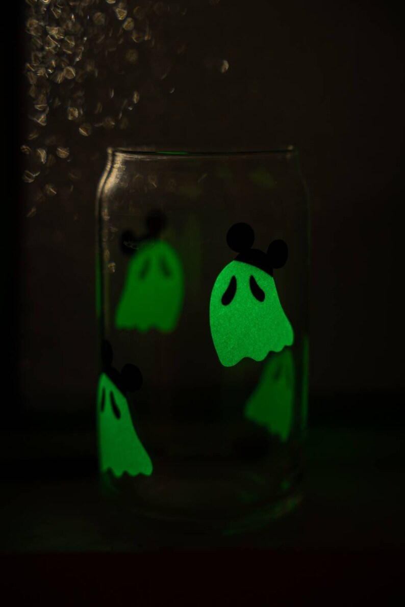 May include: A clear glass jar with glow-in-the-dark ghost stickers. The ghosts are green and have black eyes and mouths. One ghost has Mickey Mouse ears.