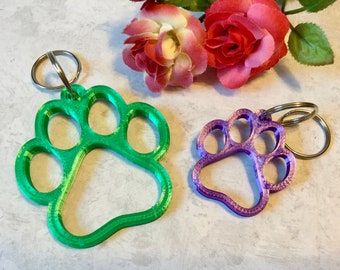 May include: Two 3D printed paw print keychains. One is green and the other is purple.