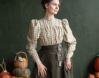 May include: A woman wearing a vintage-style outfit with a gingham blouse and a long, dark green skirt. She is standing in front of a green background with pumpkins and candles.
