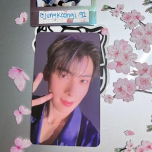 May include: Two rectangular photo cards featuring portraits of individuals. The top card shows a person in denim overalls and a striped shirt with the text @JungKoongi.92. The bottom card displays a person in a purple shirt making a peace sign.