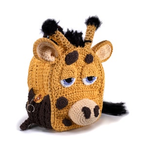 May include: A crocheted giraffe backpack with brown and black accents. The backpack has a zipper closure and a small pocket on the front. The giraffe has a brown nose, black eyes, and a blue tongue.
