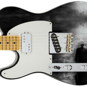 May include: Black electric guitar with a white pickguard and a black and white graphic of a person walking past a streetlight on the body.