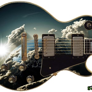 May include: A black electric guitar with a custom design featuring a blue and white planet with clouds and a bright sun. The guitar has a gold-colored hardware and a black pickguard.