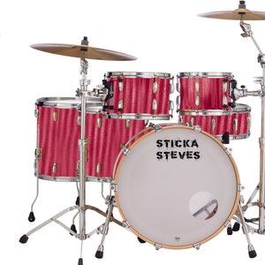 Puede incluir: Una batería roja con un bombo que dice "Sticka Steves". La batería tiene un soporte de platillos con dos platillos.