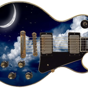 Op de afbeelding: Een zwarte elektrische gitaar met een aangepast ontwerp met een halve maan, sterren en wolken tegen een blauwe nachtelijke hemel.