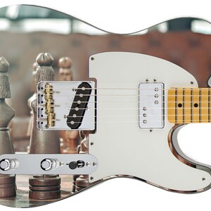 May include: A white electric guitar with a mirrored finish. The guitar has a single-coil pickup and a chrome bridge. The body of the guitar is decorated with a mirrored image of a chessboard with chess pieces.