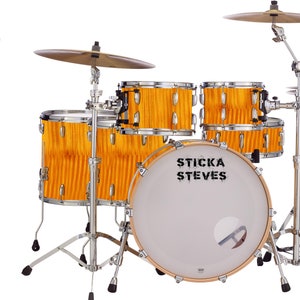 Puede incluir: Un set de batería con un acabado de madera amarilla. El bombo tiene el texto "Sticka Steves" impreso en él. El set incluye un bombo, un tambor de caja, dos toms y un hi-hat.