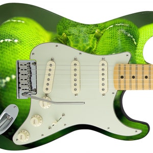 Może przedstawiać: Zielona gitara elektryczna z wzorem skóry węża. Gitara ma biały pickguard i chromowany mostek.